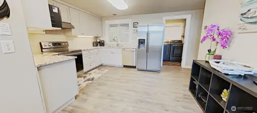 Bright and airy kitchen, with granite countertop, tile backsplash, and newer stainless steel appliances