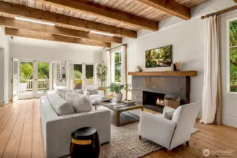 Warm and inviting living room featuring exposed wood beams, built-in shelving, and a statement fireplace.
