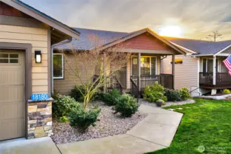 Inviting front porch with landscaped yard and sunset views