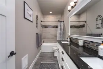 Modern full bath with tile shower, double vanity, and lighting