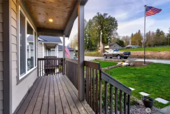 Covered front porch with wood deck and landscaped yard