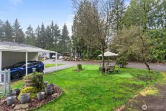 The spacious corner lot includes a landscaped lawn, shaded sitting area, and beautiful tree cover — your private nature retreat just steps from the home.