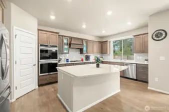 This chef-inspired kitchen features rich cabinetry, a large quartz island, double ovens, and stainless steel appliances—offering both style and functionality for everyday meals or entertaining a crowd.