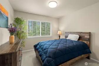 Peaceful secondary bedroom with forest views, plush carpeting, and a calming atmosphere—perfect as a guest room, kids' space, or personal retreat.