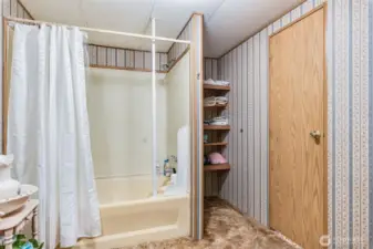 Full primary bath with shower-tub combo and built-in storage shelves.