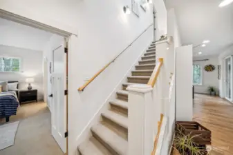 The easy access primary suite is stationed in the less active front of the home off the stairway to the second level.  Note the textured, easy care carpet and trim extras on the stair railings and posts.