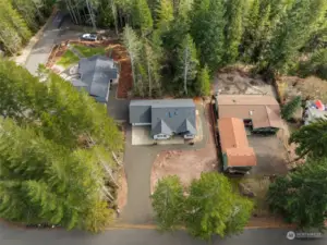 An aerial view of the home and lot shows the proximity of the other home lots. The green home has no windows looking into the front yard or home on this offered lot. The large front yard gets plenty of light and holds the septic drain field. Plant your own grass or ground cover.