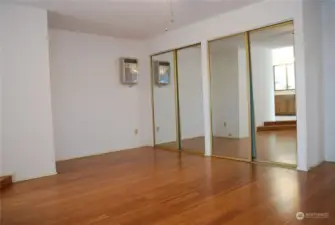 Primary suite has double mirrored closets, a wall AC unit, a ceiling fan, and new bamboo floors.