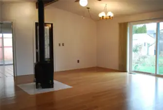 View from bedroom hall area across bamboo floored, cathedral ceiling great room towards the back slider and the kitchen & dining area.  Beautiful gas stove for warm comfort or emergency needs.