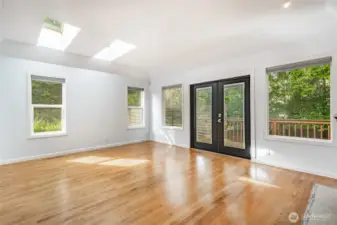 Large primary bedroom with custom fireplace and french doors leading to the deck.