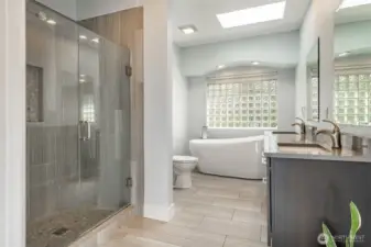 Bathroom attached to primary bedroom has soaking tub, walk-in shower, skylight, and walk-in closet.