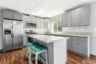 Coastal vibes with soft gray cabinets and stainless steel appliances.