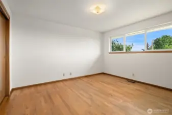 Primary bedroom shown here without the virtual staging. Original hardwoods, wood doors and trim all unpainted!