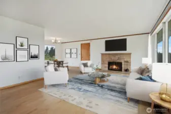 Living room with large picture windows, original hardwood floors & brick wood burning fireplace. Virtually staged to give you a sense of the space!