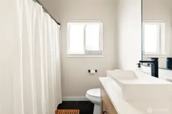 The primary bath feels like a private spa, featuring new tile floors, fresh cabinetry, stylish lighting, and elegant dual sinks.