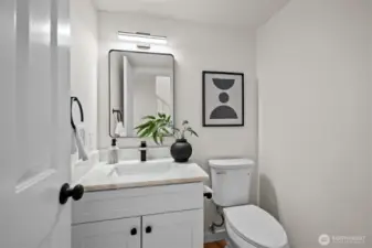 Refined and refreshed main floor powder room featuring elegant marble countertops, crisp white shaker cabinets, and stylish fixtures.