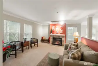 The heart of the living space is anchored by a cozy gas fireplace framed with elegant tilework and a pop of color, perfect for relaxing evenings at home. Enjoy peaceful, tree-lined views from multiple large windows—bringing the outside in while maintaining a sense of calm and privacy.