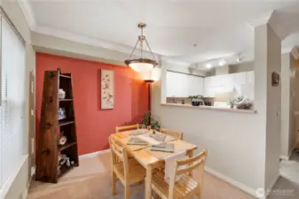 Enjoy meals in a cozy, well-lit dining area that effortlessly connects to the kitchen through a convenient pass-through bar—perfect for casual dining and easy entertaining. A warm accent wall adds character to the space, while crown molding and soft lighting create an inviting and polished feel.