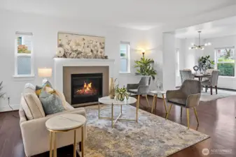 Spacious main-level living area featuring gas fireplace, large windows, and open flow to dining and kitchen.