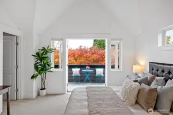 Primary suite opens to a private balcony surrounded by mature trees and fall color.