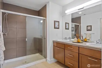 Primary bath features dual sinks, large mirror, and walk-in shower with tile surround.