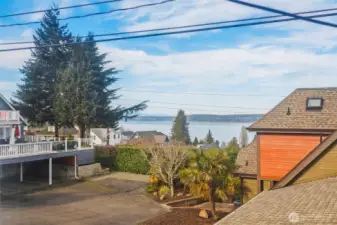 From the north bedroom, look out over the neighborhood rooftops to Puget Sound and the distant shore.