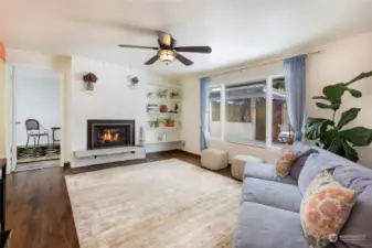 step into bright living room area w/ gas fireplace insert & backyard views