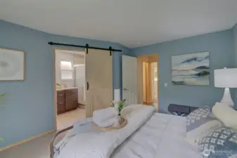 Enter the attached primary bathroom through the custom barn door.