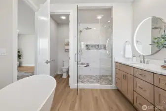Escape into a luxurious bath featuring a freestanding soaking tub, a walk-in shower with dual shower heads and bench, and a dual sink vanity. Every element has been chosen to elevate your daily routine into a moment of indulgence.