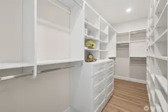 The primary suite’s spacious walk-in closet provides custom shelving and plenty of room for storage. It’s a beautifully organized space designed for both practicality and ease.
