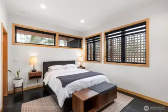 The lofty primary bedroom enjoys plenty of windows, yet offers privacy with custom blinds and a privacy fence outside. Again, radiant-heated concrete floor for comfort.