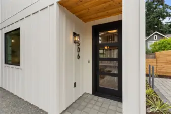 The black-framed glass front door makes a bold, modern statement—balancing transparency and privacy while anchoring the entry with sleek sophistication.