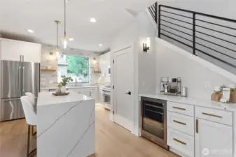 The large kitchen window floods the space with natural light, framing outdoor greenery while enhancing the airy, open feel of the room’s modern design.
