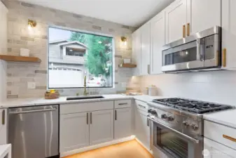 Sleek stainless-steel appliances—including a gas range, built-in microwave, dishwasher, and double-door fridge—bring modern functionality and a polished finish to this stylish kitchen.