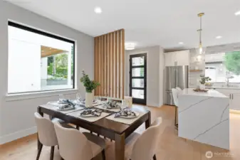 This open-concept space flows effortlessly from the dining area to the kitchen, anchored by a dramatic marble waterfall island and softened by warm wood tones and natural light—perfect for entertaining or everyday living with style and ease.
