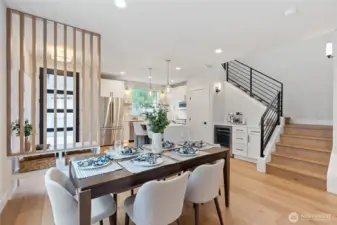 The vertical slat partition and staircase add architectural interest, while natural light and warm finishes create a welcoming, cohesive flow.