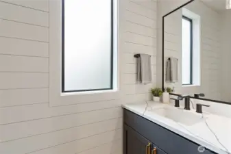 This bathroom blends crisp shiplap walls, bold black fixtures, and gold-accented cabinetry for a clean, modern look with subtle contrast and warmth.