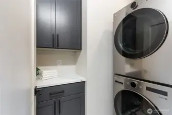 Streamlined and stylish, this laundry room pairs sleek appliances with dark cabinetry and a crisp white counter—making everyday tasks feel effortlessly refined.