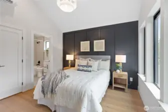 This bedroom offers a clean, modern retreat with soft textures, a dark accent wall, and vaulted ceilings—bathed in natural light for a bright, welcoming feel.