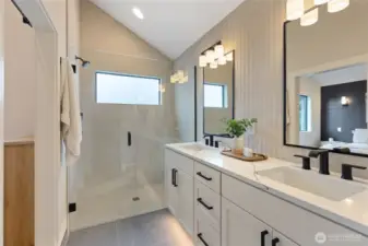 This elegant bathroom features a spacious glass shower, double vanity with black accents, and a sloped ceiling—designed for comfort, symmetry, and modern style.