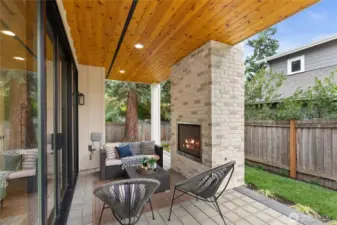 Perfect for cozy nights, this covered patio features a glowing brick fireplace, warm wood ceiling, and inviting lounge seating—all wrapped in backyard serenity.