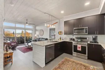 Gorgeous kitchen with modern finishes, 6-burner gas stove, glass tile backsplash, quartz countertops and eating bar. Notice the custom accent tile on the end of the countertop and the ceilings!