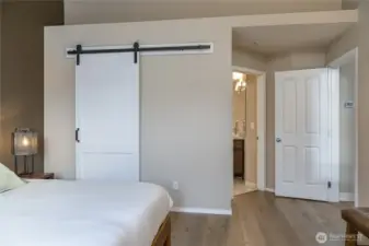 Sophisticated primary suite boasts a space-saving rolling door for the walk-in closet and a private 5-piece en-suite bath