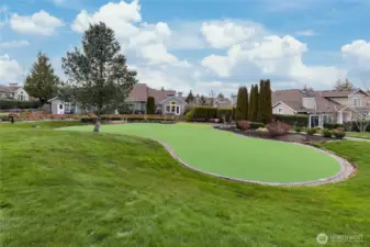 A broader view of the beautiful community putting green, showcasing the lush, park-like setting that surrounds this prime end-unit location