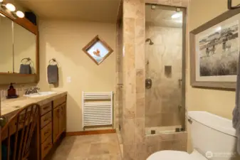 Primary bath spacious shower with Travertine tile with multiple shower heads and steamer. Heated towel rack and vanity.