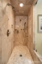 Walk in travertine tile shower with multi head spray and steam shower. Glass in shower has been treated with special coating to help stay clean.