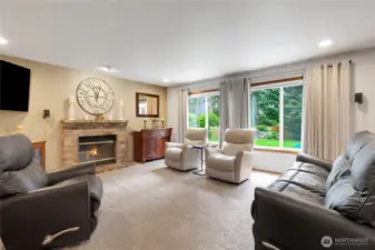 Inviting family room featuring a wood-burning fireplace and large windows that frame picturesque views of the beautiful backyard.