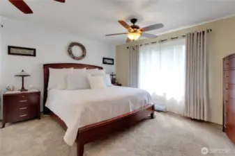 The expansive primary suite features an oversized bedroom with a large window showcasing stunning sunsets and partial mountain views. It includes a private attached bathroom and a spacious walk-in closet, offering both comfort and luxury.