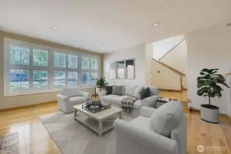 The spacious living room features gleaming hardwood floors, a wall of windows to the front and beautiful plantation shutters.