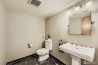 The powder room on the main floor features a pedestal sink, geometric tile floors and attractive lighting.